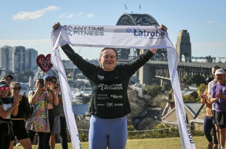 L'ex-footballeuse britannique Fran Hurndall entourée de supporteurs après avoir bouclé une course de charité de 3.800 kilomètres à travers l'Australie, le 29 juin 2025 à Sydney