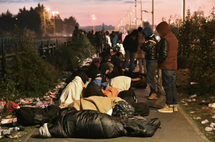 Des migrants qui ont dormi à l'extérieur se préparent à faire la queue devant un centre de transit pour évacuer la Jungle de Calais, le 27 octobre 2016