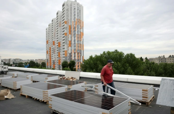 Un ouvrier installe des panneaux solaires sur le toit d'une maternité au cours d'une coupure d'électricité à Kiev en Ukraine, le 14 juin 2024, à la suite d'attaques russes contre des infrastructures électriques