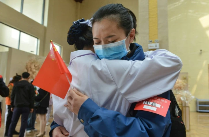 Une soignante de Xiaogan, ville de la province du Hubei au coeur de l'épidémie de coronavirus, dit au-revoir à une collègue venue prêter main forte depuis Chongquing, le 23 mars 2020 à Xiaogan