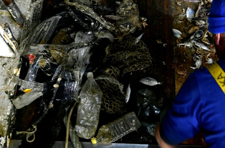 Des pêcheurs italiens remontent des poissons et des déchets en plastique dans leurs filets le 23 mai 2019 au large de San Benedetto del Tronto, en Italie