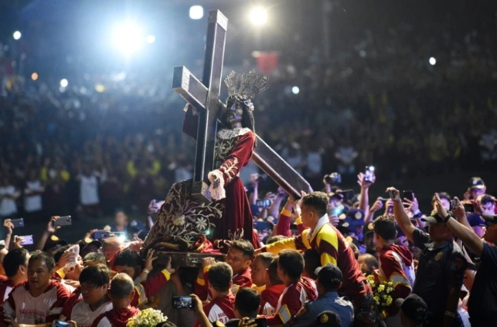 Une foule de catholiques accompagne la statue de Jésus de Nazareth portant la croix du Calvaire, lors de la procession annuelle du "Nazaréen Noir" à Manille le 9 janvier 2019