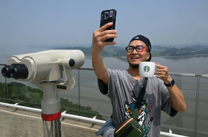 Un touriste prend un selfie avec une tasse Starbucks devant la Corée du Nord depuis une plate-forme d'observation sud-coréenne située à l'Écoparc de la Paix d'Aegibong, à Gimpo, le 1er juillet 2026 