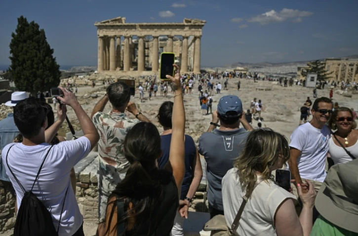 Des touristes visitent le site antique de l'Acropole, le 14 juin 2023 à Athènes