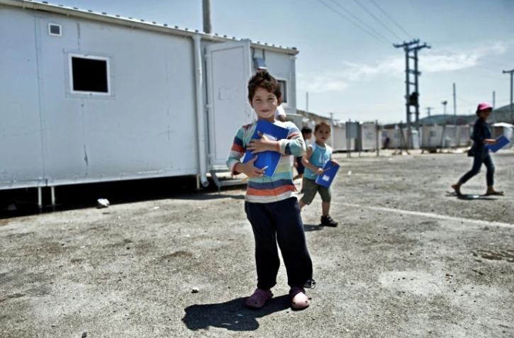 Un jeune garçon devant un conteneur reconverti en salle de classe, le 24 juin 2016 dans le camp de réfugiés de Skaramangs (sud de Athènes)