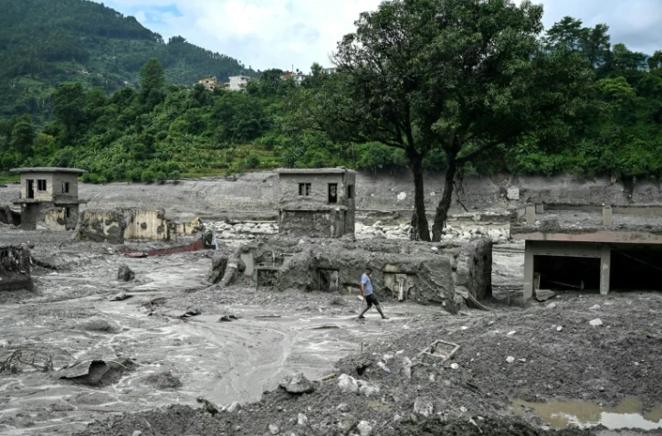 Un homme marche au milieu des décombres après la crue destructrice dans l'Himalaya, le 30 août 2026 à Trishuli, dans le district népalais de Nuwakot 