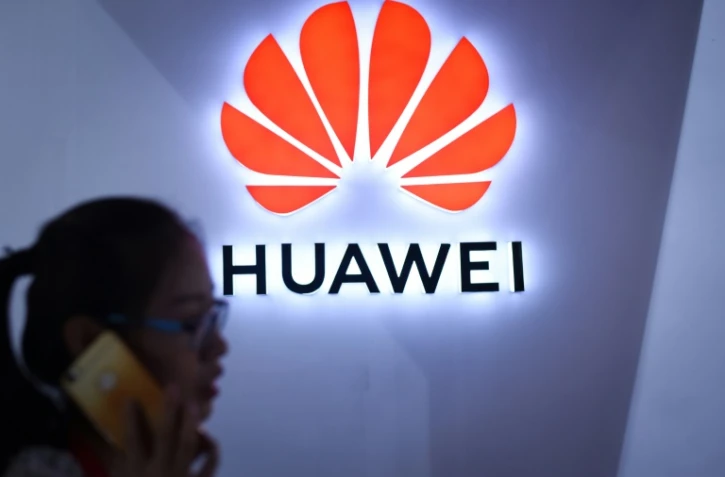 Photo d'illustration d'une femme passant devant le logo de Huawei à Pékin le 8 juillet 2018