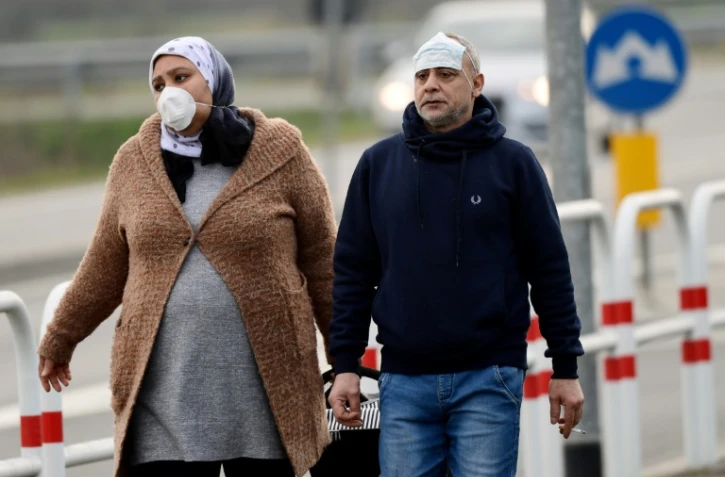 Des habitants équipés de masques de protection photographiés le 23 février 2020 à l'entrée de la petite ville de Casalpusterlengo, près de Milan en Italie, pays le plus touché en Europe par le coronavirus