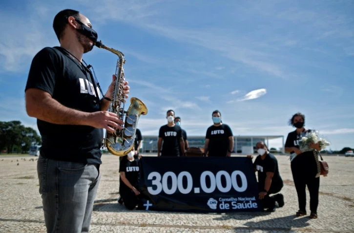 Un membre du personnel de Santé joue du saxo devant un cercueil pour dénoncer la mort de 300.000 personnes au Brésil victimes sud Covid-19 à Brasilia le 25 mars 2021