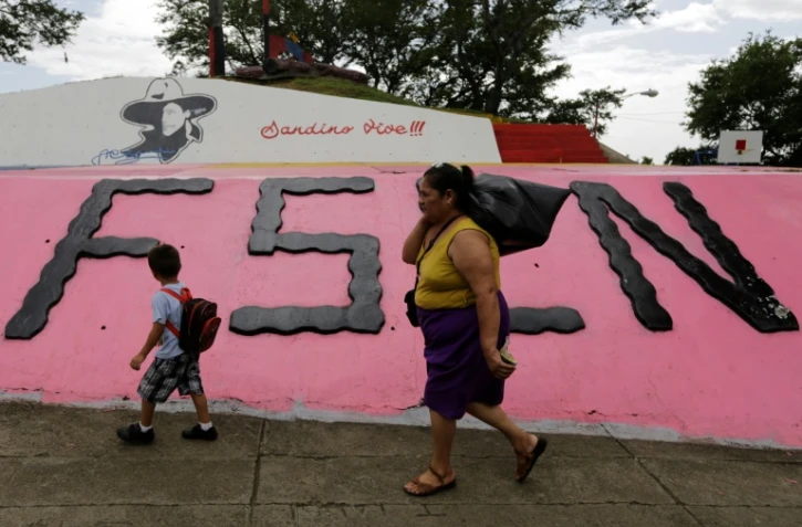 Une femme et un enfant marche devant un monument à la mémoire du révolutionnaire Augusto C. Sandino, à Managua, le 17 juillet 2018