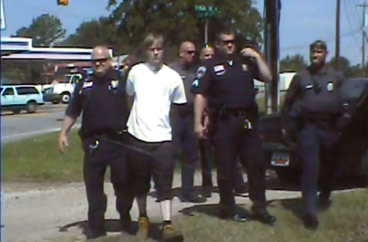 Dylann Roof, en blanc, au milieu de policiers de Shelby en Caroline du Nord après son arrestation, le 18 juin 2015