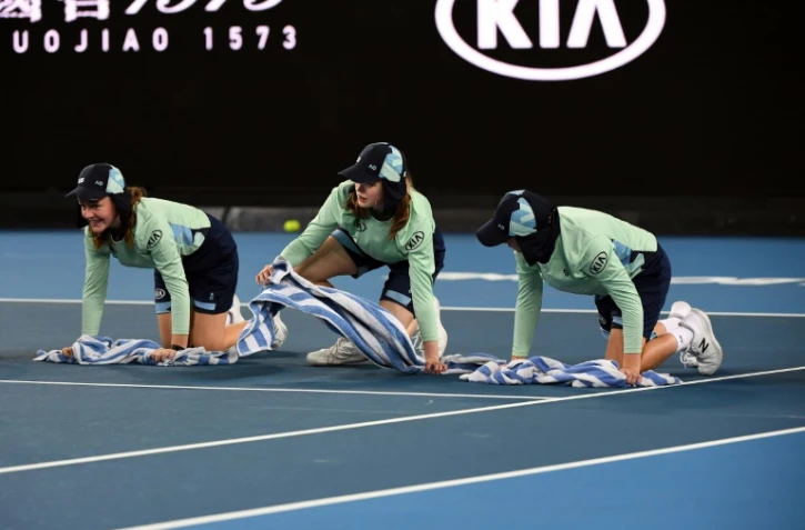 Des ramasseuses de balles épongent un court lors de l'Open d'Australie, le 20 janvier 2020 à Melbourne