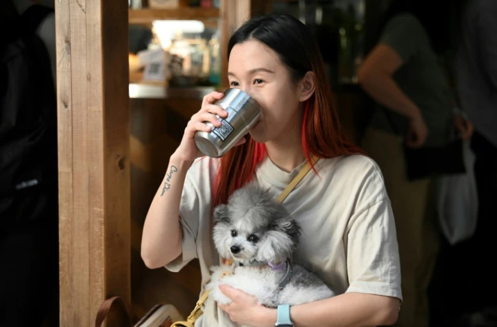 La jeune toiletteuse pour animaux Lucine Mo boit son café dans une tasse jetable isotherme dotée d'un QR code, dans un café de Hong Kong, le 2 novembre 2023