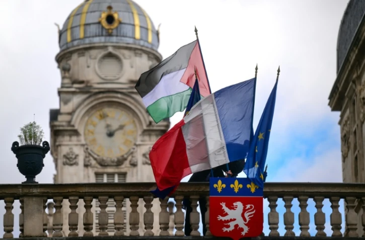 Un employé de la mairie place le drapeau palestinien à côté du drapeau français, du drapeau de Lyon et du drapeau de l'Union européenne, sur l'entrée de l'hôtel de ville de Lyon, le 22 septembre 2025