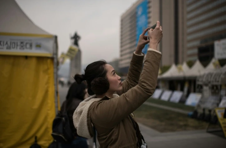 Une femme prend en photo une manifestation anti-gouvernementale, dans le centre de Séoul, le 3 novembre 2016