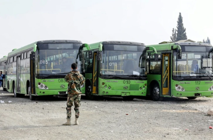 Photo de bus stationnés au point de passage de Wafidine, entre la capitale syrienne Damas, et l'enclave rebelle dans la Ghouta orientale, dans l'attente d'évacuations, le 13 mars 2018