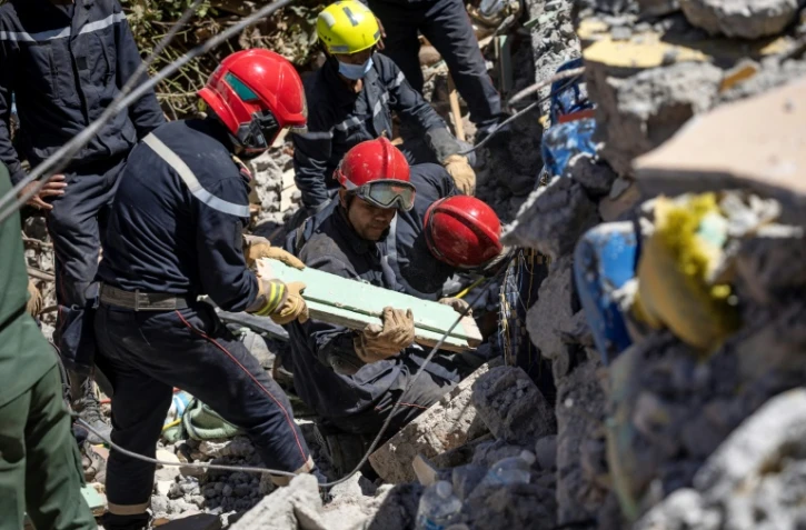 Des sauveteurs marocains et espagnols fouillent les décombres d'une maison détruite par le séisme dans le village de Talat N'Yacoub, au Maroc, le 11 septembre 2023