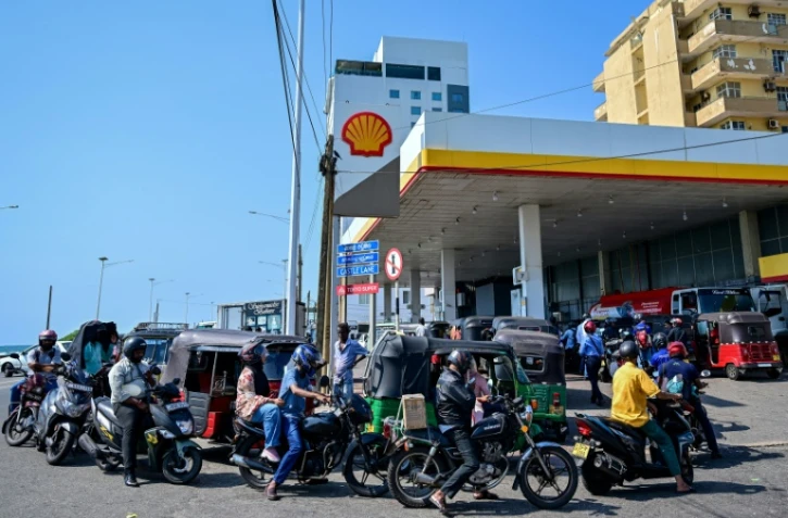 Des motoyclistes font la queue pour prendre du carburant à une station-service de Wellawatte, près de Colombo, le 16 mars 2026 au Sri Lanka 