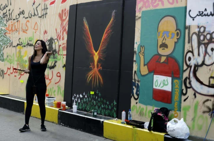 Une artiste libanaise Hayat Nazer devant son phoenix peint sur le mur, le 6 novembre 2019 à Beyrouth