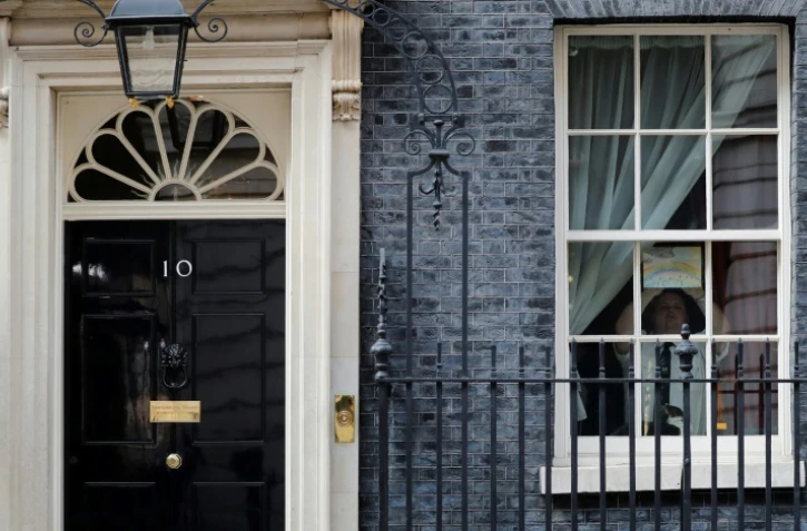Un employé du 10 Downing Street colle sur la fenêtre de la résidence du Premier ministre le dessin d'un arc-en-ciel, symbole de l'espoir, le 9 avril 2020
