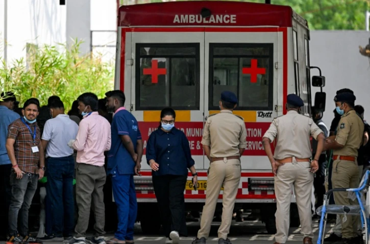 Des policiers et des membres du personnel médical près d'une ambulance stationnée devant une morgue d'hôpital à Ahmedabad, le 15 juin 2025
