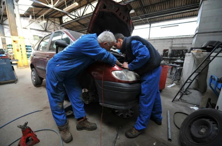 Un mécanicien et un apprenti travaillent dans un garage à Hérouville-Saint-Clair, dans le Calvados, le 24 avril 2008