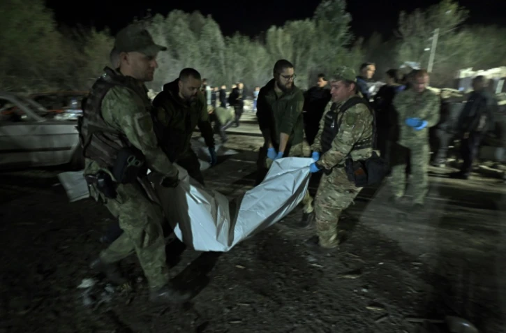 Des policiers ukrainiens portent le corps d'une victime tuée dans une frappe russe, le 5 octobre 2023 à Groza (Ukraine)