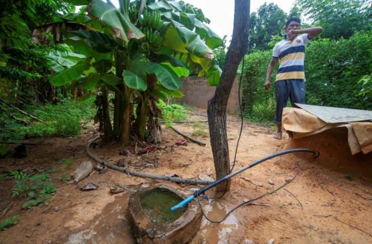 Un homme puise de l'eau d'un puits dans un quartier de Maracaibo, dans l'État de Zulia, au Venezuela, le 21 juin 2025