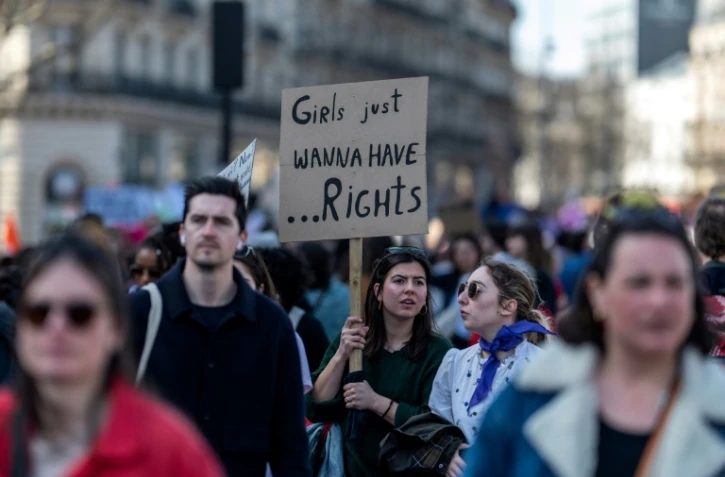 Une manifestante brandit une pancarte proclamant "Grils just wanna have... rights" ("Les filles veulent juste avoir des droits"), lors de la manifestation pour la journée internationale des droits des femmes, le 8 mars 2025 à Paris