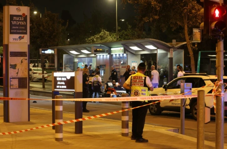 Des policiers et ambulanciers entourent un blessé allongé sur le sol après une attaque au couteau à une station de tramway, le 21 septembre 2023 à Jérusalem