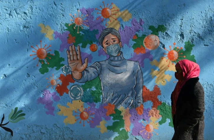 Une femme portant un masque devant une peinture murale à New Delhi le 19 décembre 2020