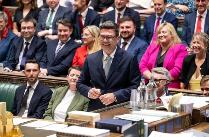 Photo diffusĂ©e par le Parlement britannique du nouveau dĂ©putĂ© travailliste de Makerfield, Andy Burnham (c), souriant, après avoir signĂ© le registre Ă la suite de sa prestation de serment Ă la Chambre des communes, le 22 mai 2026 Ă LondresÂ