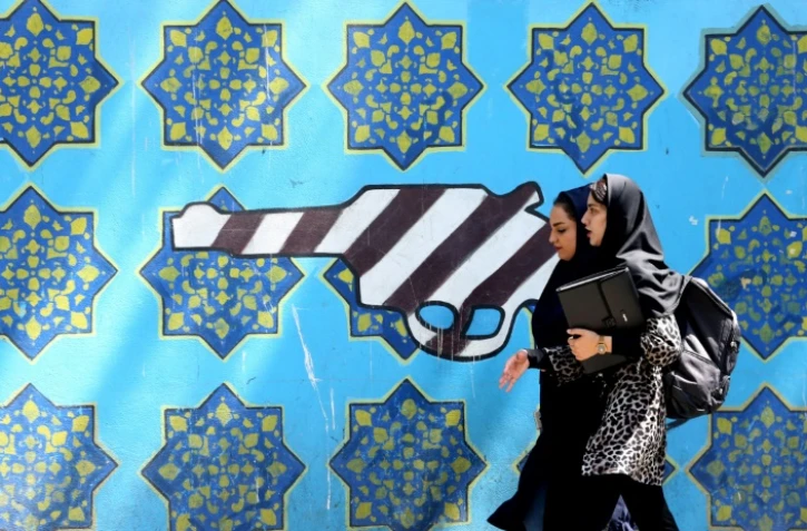 Des Iraniennes passent devant une peinture sur le mur de l'ancienne ambassade américaine à Téhéran, le 22 juin 2019