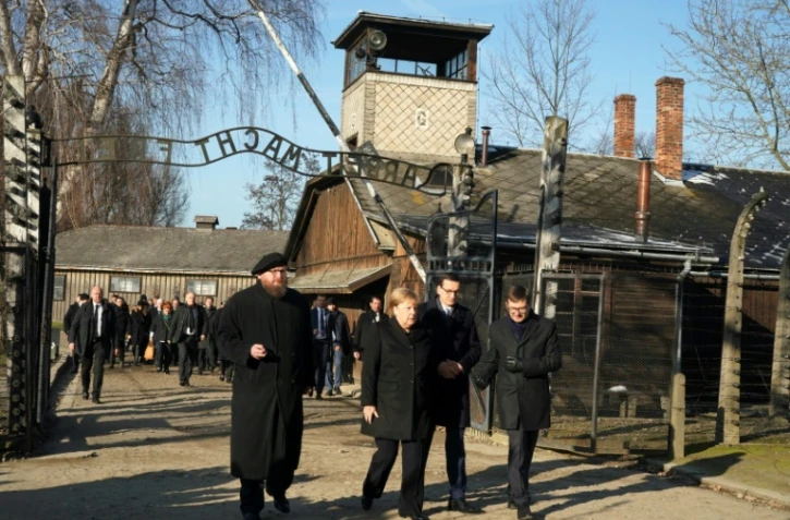 La chancelière allemande Angela Merkel (2è g) avec le Premier ministre polonais Mateusz Morawiecki (2è d) et le directeur du musée de Auschwitz-Birkenau Piotr Cywinski (g) franchit l'entrée du camp de l'ancien camp de Auschwitz-Birkenau, le 6 décembre 2019