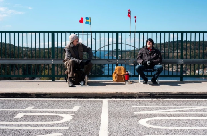 Pontus Berglund (g) et son frère jumeau Ola bavardent, l'un en Suède, l'autre en Norvège, sur le pont reliant les deux pays, le 1er mai 2021 à Svinesund