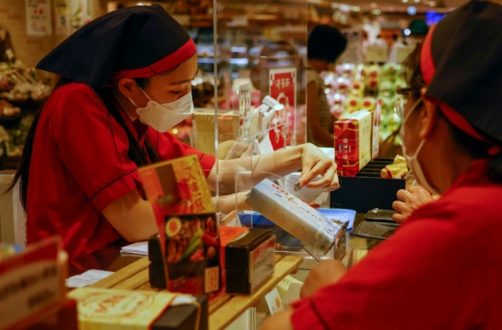 Une vendeuse rend la monnaie à un client dans un magasin alimentaire de Tokyo, le 29 juillet 2021