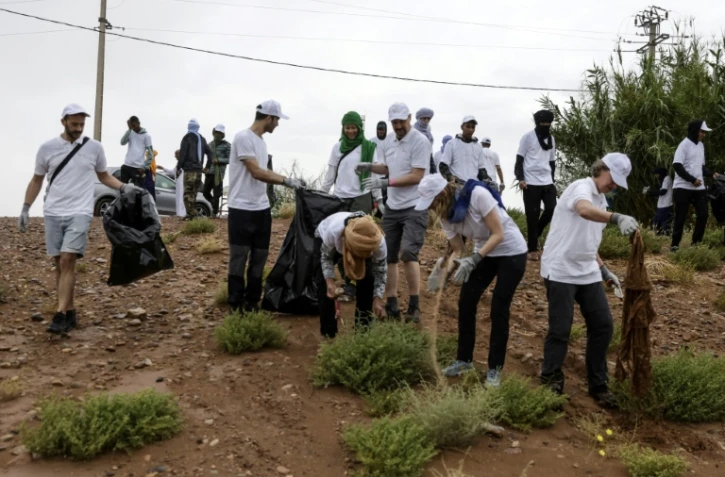 Des bénévoles ramassent des déchets lors d'une campagne de nettoyage de M'Hamid El Ghizlane, aux portes du désert, dans le sud Maroc, le 12 avril 2025