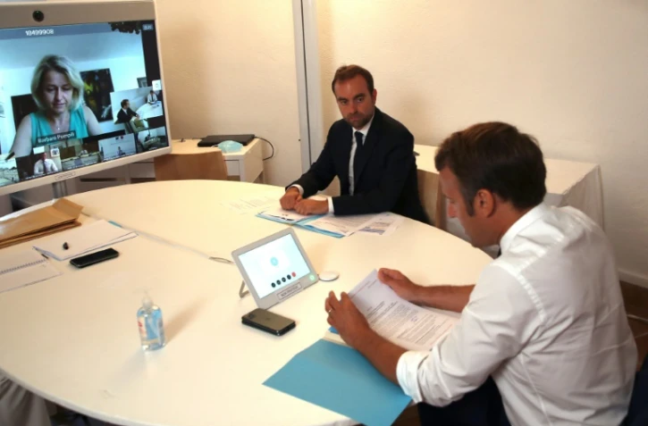 Le président Emmanuel Macron (d) et le ministre des Outre-mer Sébastien Lecornu (c), avec la ministre de la transition écologique Barbara Pompili (sur l'écran), lors d'une visio-conférence depuis le Fort de Bregançon, le 11 août 2020