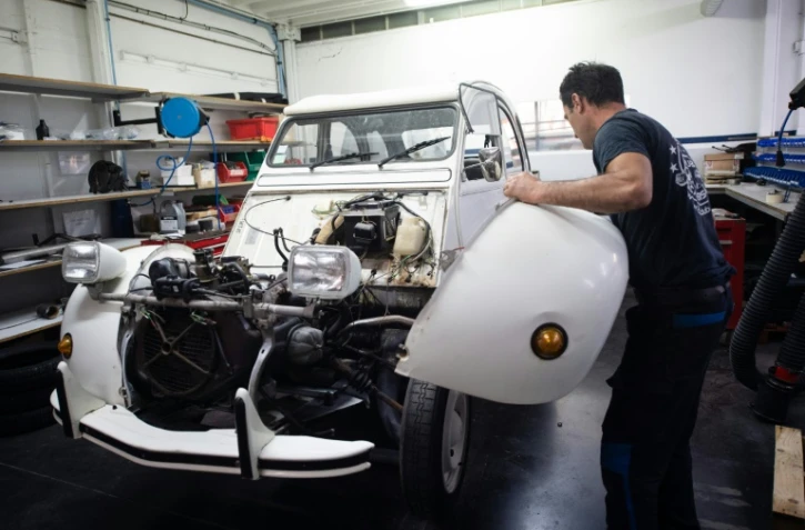 Dans les ateliers du Mehari Club de Cassis (Bouches-du-Rhône), un mécano extrait le moteur thermique d'une ancienne 2CV pour en installer un autre électrique, le 9 juillet 2020