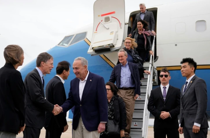Une délégation de sénateurs américains menée par le chef de la majorité au Sénat, Chuck Schumer (c), arrive à l'aéroport de Shanghai, en Chine