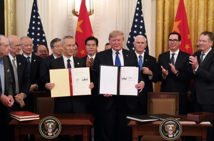 Le Vice-Premier ministre chinois Liu He et le président américain Donald Trump montrent aux photographes l'accord commercial partiel signé entre les deux puissances, le 15 janvier 2020 à la Maison Blanche 