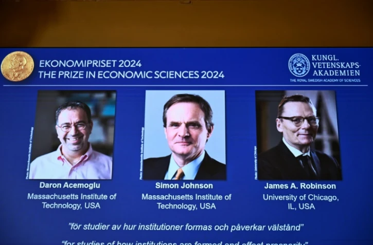 (g-d) Les portraits des lauréats du prix Nobel d'économie, l'Américano-turc Daron Acemoglu, et les Britano-américains Simon Johnson et James A. Robinson, à l'Académie royale des sciences de Suède, le 14 octobre 2024 à Stockholm 