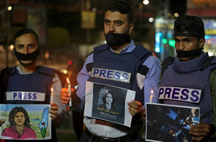 Des journalistes tenant des bougies à la main et des posters de la journaliste palestinienne tuée Shireen Abu Akleh, lors d'une cérémonie à Rafah dans la bande de Gaza, le 11 mai 2022 
