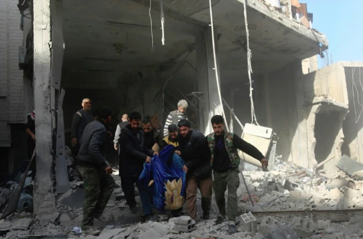 Des habitants de Hamouria transportent le corps d'une victime après un bombardement, dans la Ghouta orientale, le 3 décembre 2017 en Syrie