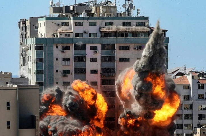 Des boules de feu jaillissent d'un bâtiment qui abritait les locaux de médias internationaux, pulvérisé par une frappe israélienne, le 15 mai 2021 à Gaza