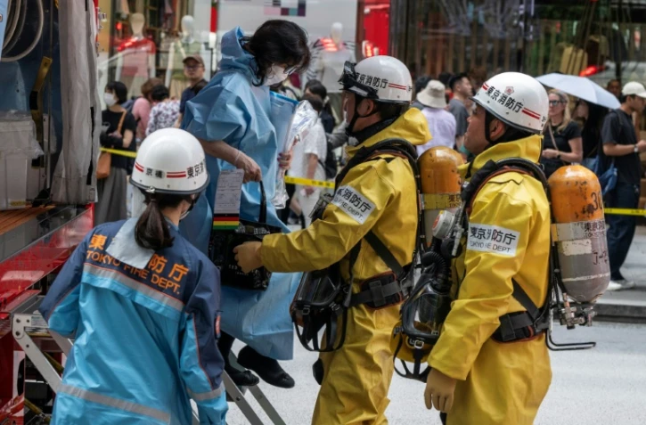 Les secours aident une femme qui était dans un centre commercial quand un homme y a pulvérisé une substance, à Tokyo, le 25 mai 2026