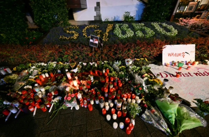 Des bougies et des fleurs, avec l'inscription "pourquoi? vous n'êtes pas seuls", déposées le 24 août 2024 en hommage aux victimes non loin du lieu où trois personnes ont été tuées la veille à Solingen en Allemagne