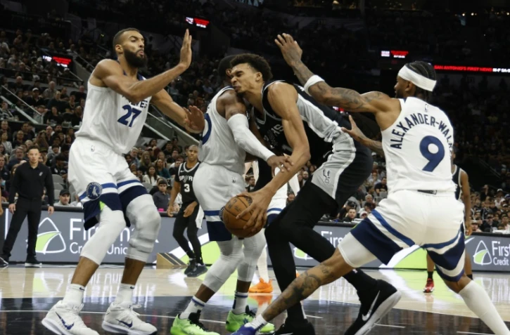 Victor Wembanyama (c.), la star des San Antonio Spurs, est entouré par trois joueurs des Minnesota Timberwolves, Rudy Gobert (g.), Mike Conley, et Nickel Alexander-Walker (d.), lors d'un match de NBA, à San Antonio, le 2 novembre 2024