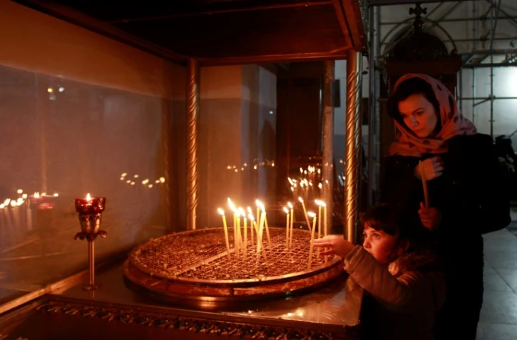 Une chrétienne et son fils allument des cierges le 20 décembre 2016 dansl'Eglise de la Nativité, à Béthléem en Cisjordanie, où Jésus-Christ est né selon la Bible