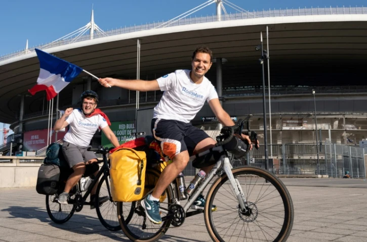 Mehdi Balamissa (à droite) et Gabriel Martin agitent des drapeaux français avant leur départ le 20 août 2022 du Stade de France vers Doha, en vélo, pour aller encourager les Bleus à la Coupe du monde 2022 au Qatar